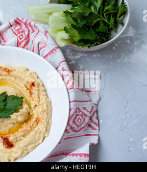 Home classic hummus con sedano, pita. Vista dall'alto sul cemento grigio Sfondo. Cibo Vegan concetto. Foto Stock