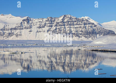 Montagne coperte di neve lungo il ghiacciaio Jökulsárlón laguna in inverno, lago glaciale nel sud-est dell'Islanda Foto Stock