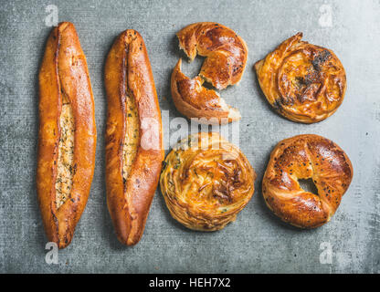 Stile orientale pasticceria turco con diversi riempimenti su pietra grigia sfondo, vista dall'alto. Bagel con sesamo nero, Borek con spinaci e papavero vedere Foto Stock