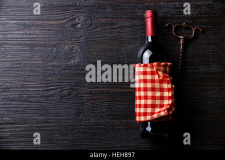 Bottiglia di vino e un cavatappi su nero di legno bruciato sfondo spazio di copia Foto Stock