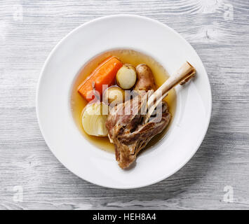 Stufato khashlama zuppa con carne di agnello e patate e carote in piastra su sfondo di legno Foto Stock