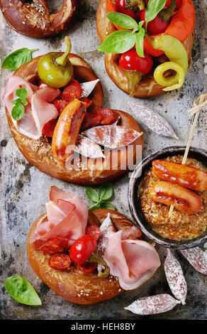 Varietà di spuntini a base di carne salsicce fritte, wienerwurst, prosciutto, marinato al peperoncino servito in salati salatini con basilico fresco e senape sopra il vecchio metallo Foto Stock