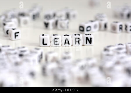 Cubi di plastica lettere che compongono la parola imparare su sfondo bianco Foto Stock