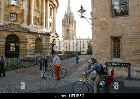 Oxford, Inghilterra, la maggior parte degli studenti vanno in giro in bicicletta o a piedi di Oxford. A sinistra è la Radcliffe Camera, centro di St. Mary e Chrurch diritto Brasenose Lane. Foto Stock