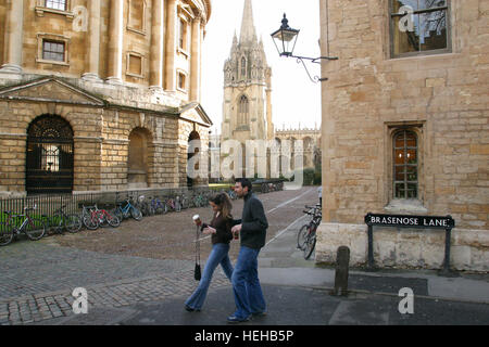 Oxford, Inghilterra, la maggior parte degli studenti vanno in giro in bicicletta o a piedi di Oxford. A sinistra è la Radcliffe Camera, centro di St. Mary e Chrurch diritto Brasenose Lane. Foto Stock