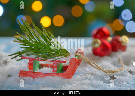 Red sleigh giocattolo e albero di Natale sulla neve falsa Foto Stock