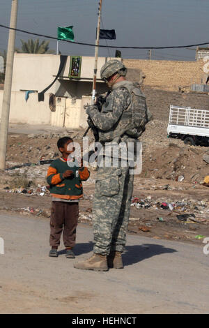 Sgt. Joshua Oden, un San Angelo, Texas, nativo, dà un ragazzo un pezzo di candy durante una pattuglia nel Rashidiayah Nahia nel nord di Bagdad, Dic 30. Oden è un fante con sede e Sede Società, 1° Battaglione, 27 Reggimento di Fanteria "Wolfhound," seconda Stryker Brigade Combat Team 'Warrior", XXV divisione di fanteria, attualmente fissata al 3° BCT, quarto Inf. Div., Division-Baghdad multinazionali. Wolfhound soldato incontra i bambini iracheni 139989 Foto Stock