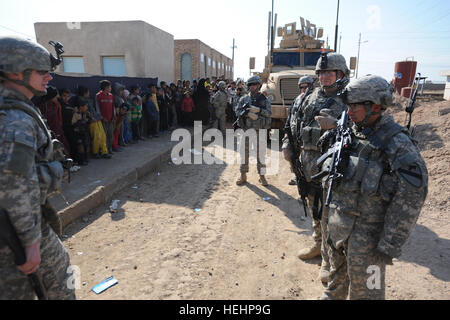 Stati Uniti Cavalleggeri dal 1° Stormo, 9° reggimento di cavalleria, quarta brigata Team di combattimento, 1° Divisione di cavalleria, mantenere l ordine come ragazzi iracheni dalle aree rurali Maysan provincia, Iraq, line up per cure mediche presso la clinica di Beni Hashim. Questo civile impegno militare porterà di forniture mediche e servizi per l'area, 25 gennaio, 2009. Clinica Medica nella rurale provincia Maysan 147727 Foto Stock