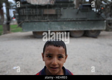 Un ragazzo iracheno sorrisi per la telecamera mentre un Stryker veicolo da combattimento da società A, 1º Battaglione, 111Reggimento di Fanteria, 56th Stryker Brigade Combat Team, ventottesima divisione di fanteria, Pennsylvania National Guard, Division-Baghdad multinazionali, fornisce la sicurezza per le truppe smontati in Nadeem Village, Iraq, Marzo 4, 2009. Pattugliamento comune vicino a Taji 156484 Foto Stock