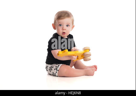 Un otto mesi baby boy giocare con un giocattolo di legno. Isolato su uno sfondo bianco. Foto Stock