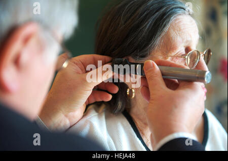 Medico di Medicina Generale medico esamina anziani femmina casa di cura paziente orecchie durante il GP di routine appuntamento sul NHS Foto Stock