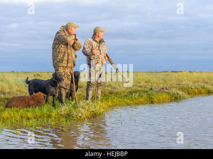 Regno Unito Wildfowlers o sparatutto d'anatra si fermò sulla palude o foreshore in lo sbiadimento della luce della sera Foto Stock