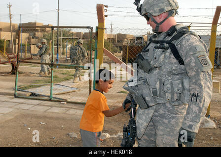 Sgt. Andy Zeigler, nativo di Dumas, Texas, un poliziotto militare assegnato alla società di sede, la brigata di truppe speciali Battaglione, 3° Brigata Team di combattimento, ottantaduesima Airborne Division scuote le mani con un bambino davanti a un parco giochi di nuova Baghdad, 30 aprile. Pantere rendere orme nella nuova Baghdad 169543 Foto Stock