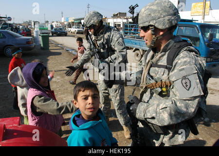 San Antonio, Texas, nativo, Staff Sgt. Adrian Gonzalez, combattere medic, con il 2° Stryker Brigade Combat Team, 'Warrior", XXV divisione di fanteria per la sicurezza personale di distacco, diritto e Houston, Texas, nativo, Staff Sgt. Wesley Drake, operatore radio, con il 2° SBCT, XXV Inf. PSD, interagire con gli enti locali di bambini iracheni, 14 gennaio durante una pattuglia attraverso il mercato Taji. Gonzalez ha detto che ama interagire con i bambini quando egli esce su missioni. Era chiaro che i bambini è piaciuto molto quando ha visitato, perché i bambini sono stati il tifo Gonzo, bizzarri, bizzarri, un nickname ha detto ai ragazzi di chiamarlo, Foto Stock