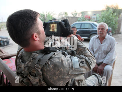 Un U.S. Soldato da 3° plotone, società azteca, 2° Battaglione, XXIII Reggimento di Fanteria, quarta brigata Stryker, seconda divisione di fanteria fotografie un iracheno in Taji, Iraq, 21 maggio. Il plotone è stata la verifica dell'identità degli iracheni selezionato per ricevere denaro per un progetto agricolo. La verifica di un documento d'identità 284509 Foto Stock