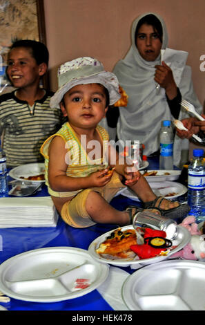 Aviosuperficie di Bagram, Afghanistan - un giovane ragazzo afgano siede nel mezzo di una tabella si gode il suo primo mai un trancio di pizza a pizza party, Giugno 19, mantenuta per circa 30 locali bambini afgani che il personale Sgt. Derek Melendez, un soldato con CJTF-1/RC-East, che ha voluto dare alla comunità in luogo di una festa di addio per se stesso all'ospedale egiziano. (Foto di U.S. Army Sgt. Kim Browne, CJTF-1/RC-Est PAO) soldato dà bambini afgani il gusto della cultura statunitense 421755 Foto Stock