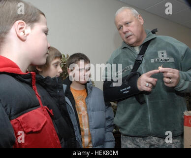 L'Indiana aiutante generale; il Mag. Gen. R. Martin Umbarger spiega i simboli per la sua sfida personale moneta per gli studenti; Brandon Albright; Giosuè Shepard; e Zackery Albright; a Stout Campo Scuola elementare; Dic. 6; 2010. Gli studenti sono stati destinatari di cappotti da Indiana Guardia Nazionale donazioni dei dipendenti come parte del 'calde mani; riscaldare i cuori' programma. Migliora la vita una mano in un momento 347578 Foto Stock