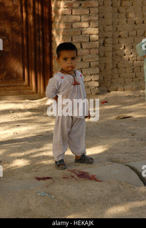 A Kandahar, Afghanistan - un giovane bambino da "vecchi Corps' area di Kandahar City intensamente orologi di un gruppo di soldati da 202nd Polizia Militare Company, 504th Polizia Militare battaglione, attualmente fissata al 1° Brigata Team di combattimento, Task Force "Raider', 4a divisione di fanteria, come essi conducono una smontata piedi patrol davanti a una cerimonia del taglio del nastro che ha significato l'apertura ufficiale di un nuovo campo di calcio in sub distretto uno di Kandahar City. Il nuovo campo è stato uno dei tanti progetti guidato da TF "Raider' e le loro forze di sicurezza nazionali afgane partner nella loro joint-gli sforzi di ricostruzione Foto Stock