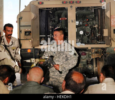 Sgt. Gilbert Britto di alfa Company, 640th aviazione battaglione di supporto e a San Diego, California, nativo, mostra una classe di esercito iracheno personale di un ugello di rifornimento di carburante e di come essa si collega al modulo di carburazione su una pesante Mobilità Estesa Tactical Carrello a Camp Taji, Iraq, Sett. 13, 2011. California guardie treno iracheni su HEMTT camion di carburante 466184 Foto Stock