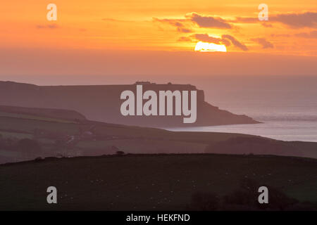 St Aldhelm di testa, Dorset, Regno Unito. 22 dicembre 2016. Regno Unito Meteo. Il sole sorge drammaticamente dietro un velo sottile di cloud su St Aldhelm di testa su Jurassic Coast di Dorset, visto dalla collina Whiteway su un freddo, calmo mattino. Foto di Graham Hunt/Alamy Live News Foto Stock