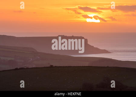 St Aldhelm di testa, Dorset, Regno Unito. 22 dicembre 2016. Regno Unito Meteo. Il sole sorge drammaticamente dietro un velo sottile di cloud su St Aldhelm di testa su Jurassic Coast di Dorset, visto dalla collina Whiteway su un freddo, calmo mattino. Foto di Graham Hunt/Alamy Live News Foto Stock