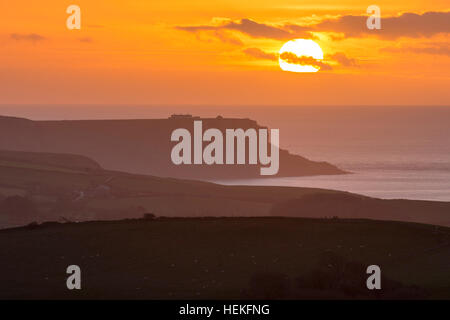 St Aldhelm di testa, Dorset, Regno Unito. 22 dicembre 2016. Regno Unito Meteo. Il sole sorge drammaticamente dietro un velo sottile di cloud su St Aldhelm di testa su Jurassic Coast di Dorset, visto dalla collina Whiteway su un freddo, calmo mattino. Foto di Graham Hunt/Alamy Live News Foto Stock