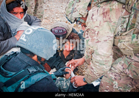 Provincia KHOWST, Afghanistan - STATI UNITI Army Sgt. Courtney Sanders, nativo di Austin, Texas e ora un medic con terzo plotone, batteria A, 2° Battaglione, 377 campo paracadute reggimento di artiglieria, Task Force Spartan, aiuta un membro dell'afghano di polizia in uniforme tendono a la ferita al piede di un ragazzo afghano in un piccolo villaggio vicino a inoltrare una base operativa Salerno febbraio 3. Il ragazzo ha gravemente inciso il suo piede su una ruota per bicicletta, era stato portato a soldati della società durante la loro ultima missione attraverso il villaggio. L'unità non frequenti missioni che li prende attraverso questo particolare villaggio e Sander Foto Stock