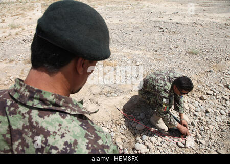 Un esercito nazionale afghano istruttore, diritto, assegnato alla quarta Kandak, 203rd Corps mostra uno dei suoi sergenti come rimuovere una linea del cavo di detonazione di un esplosivo improvvisato dispositivo durante una formazione sul campo di battaglia esercizio luglio 30, 2012, in avanti una base operativa gambo, provincia di Logar, Afghanistan. (U.S. Esercito foto di Sgt. Austin Berner/RILASCIATO) Esercizio in Afghanistan 120730-A-BZ540-026 Foto Stock