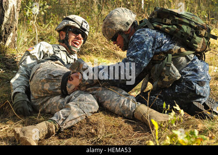 Stati Uniti Navy Corpsman ospedale di seconda classe Sean Miller (destra), assegnato in Europa Regional Medical comando, si applica un laccio emostatico per simulare un incidente durante il combattimento lane a U.S. Europa dell'esercito di esperti di settore Medical Badge in concorrenza Grafenwoehr, Germania, Sett. 18, 2012. US Army Europa campo esperto Badge Medica 2012 120918-A-BS310-039 Foto Stock