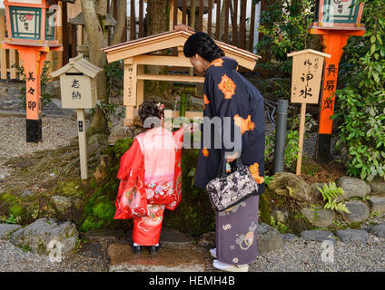 Raccogliendo l'acqua santa presso il santuario Yasaka a Kyoto, Giappone Foto Stock