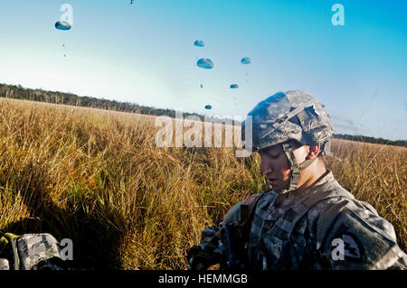 Stati Uniti Pfc dell'esercito. Angelo Wilson, con Delaware Company, 1° Battaglione, 501Reggimento di Fanteria, quarta brigata di fanteria combattere Team (airborne), XXV divisione di fanteria, che saluta da Merced, California, fissa la sua apparecchiatura dopo il paracadutismo in Shoalwater Bay Area Formazione, Queensland, Australia, luglio 20 come parte di talismano Saber 2013. Talismano Saber combina 18.000 U.S. personale e 9.000 personale australiano per evidenziare i due paesi " alleanze e funzionalità. (U.S. Esercito foto di Sgt. Eric-James Estrada /rilasciato) 4-25 Airborne Jump 130720-A-XX999-002 Foto Stock