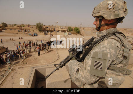 Stati Uniti Esercito 1Lt. John Costello dalla truppa a, 1-10 Battaglione, 3° Brigata, terza divisione di fanteria, fornisce la sicurezza dal tetto della Clinica Medica in Narhwan, Iraq, come gruppo iracheno di uomini, donne e bambini, la linea fino al di fuori e aspettare di essere visto da parte degli Stati Uniti Army Medics da Charlie Company, 203rd il supporto medico Battaglione, e terzo squadrone, 1° reggimento di cavalleria, 3° Brigata, terza divisione di fanteria, insieme con alcuni medici iracheni, Ott 8. Med-Op 61897 Foto Stock