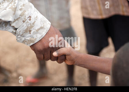 Marine Lt. Col. Aaron Potter, 3a bassa altitudine la difesa aerea comandante del battaglione, fuori di Camp Pendleton, California, scuote le mani con i figli di Nagad, Gibuti, a seguito della dedicazione di un serbatoio di acqua nel loro villaggio dic. 15. Nagad è situato nei pressi di Camp Lemonier, dove i Marines sono di stanza. 3° LAAD fornisce risorse essenziali per chiudere gli amici 69622 Foto Stock