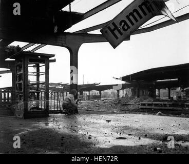 Avviso per gli spostamenti del nemico, PFC. Armand Rindone, Philadelphia, Pa., si accovaccia con una carabina presso la stazione ferroviaria in appena catturato Città di Hamm, Germania. Il 6 aprile 1945. T4c. Vernon M. Sharette. (Esercito) Nara il file #: 111-SC-203836 guerra & CONFLITTO PRENOTA #: 1093 HammApril1945 Foto Stock