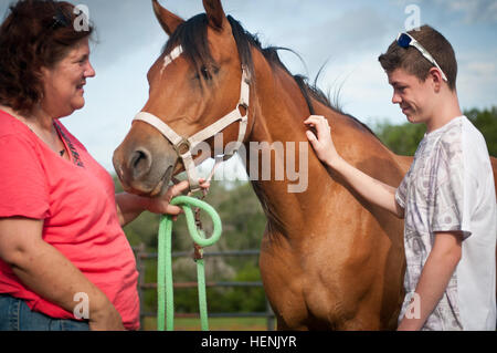 Donna Otabachian, il direttore esecutivo della stella guarigione con cavalli ranch, conduce un equino sessione terapeutica con Roger Flores-Hoops, 14, chi soffre di PTSD secondario, 17 giugno 2014. SHWH, situato sulla tentacolare Parrie Haynes Ranch a Sud di Fort Hood, è un'organizzazione dedicata alla guarigione a tutti coloro che hanno subito traumi, PTSD e PTSD secondario. PTSD secondario è subito principalmente dai bambini del servizio i membri che hanno PTSD, come essi possono essere traumatizzati da cambiamenti nei loro genitori' personalità e i conflitti che derivano da tali modifiche. SHWH ha aiutato molti di questi chil Foto Stock