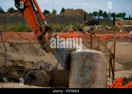 La benna di un escavatore gestiti da imprenditori belgi si muove un serbatoio come le aree intorno a getto ex siti di stoccaggio di carburante su Wingene Air Base sono scavate al fine di rimuovere, test e se necessario, decontaminare il suolo in Wingene, Belgio, 20 giugno 2014. Il lavoro è coordinato tra il corpo degli ingegneri, la Divisione Ambientale, Dipartimento di opere pubbliche, United States Army Garrison Benelux, e il ministero della difesa belga. (U.S. Esercito foto di Visual Information Specialist Pierre-Etienne Courtejoie-Released) POL decontaminazione USAG Benelux 140620-A-BD610-017 Foto Stock