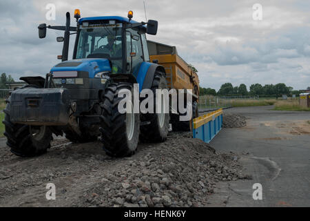 Un trattore ed il suo rimorchio riempito di terra che circondava un ex jet fuel sito di storage, passa attraverso le ruote di una zona di decontaminazione su Wingene Air Base, Wingene, Belgio, 20 giugno 2014. Il lavoro è coordinato tra il corpo degli ingegneri, la Divisione Ambientale, Dipartimento di opere pubbliche, United States Army Garrison Benelux, e il ministero della difesa belga. (U.S. Esercito foto di Visual Information Specialist Pierre-Etienne Courtejoie/piastra Released-License sfocata) POL decontaminazione USAG Benelux 140620-A-BD610-051 Foto Stock