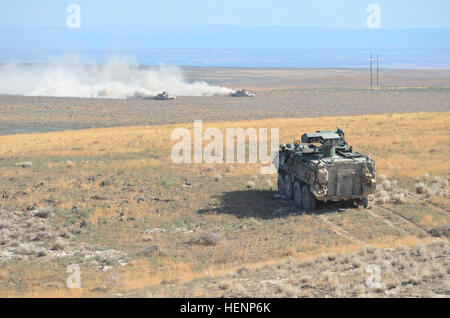 Un M1134 Anti-Tank missile guidato il veicolo (a destra) dal 1° Stormo, quattordicesimo Reggimento di Fanteria, 3° Stryker Brigade Combat Team, Base comune Lewis-Mccorda, nello Stato di Washington, che agisce come un membro della forza di contrasto durante un combattimento esportabile capacità di formazione esercizio, si prepara a agguato due M1A2 SEP Abrams da 116Brigata di cavalleria contro la squadra, Idaho Esercito Nazionale Guardia, mentre in Orchard Combat Training Center, a sud di Boise, Idaho, 14 agosto 2014. "L'azienda ATGM, hanno dimostrato di essere estremamente letale qui fuori contro i carri armati e in Bradleys,' detto comando Sgt. Il Mag. Sean Mayo, Bridgeport, in Connecticut, nati Foto Stock