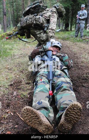 Un candidato partecipante nel 2014 U.S. Esercito Europa Campo di esperti medici evento Badge trascina una simulazione di incidente in una posizione sicura sett. 2 all'Grafenwoehr Area Formazione. Il EFMB è un badge guadagnato da personale militare che ha giocato in diverse caratteristiche fisiche e prove scritte che determinano la loro capacità di andare al di là e al di sopra e di eseguire in modo efficace le attività di medico mentre si trova in un ambiente ostile. Esercito aiuto cuochi EFMB carburante candidati 140902-A-GM630-003 Foto Stock