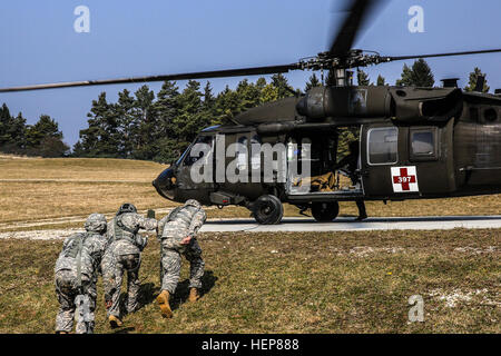 Stati Uniti I soldati dell esercito di combattimento 212th ospedale di supporto, 30 Brigata medica caricare un UH-60 Black Hawk elicottero durante la multinazionale medic training presso la multinazionale comune disponibilità centro in Hohenfels, Germania, 24 marzo 2015. Lo scopo di questo evento è per la multinazionale soldati per ottenere la ricertificazione annuale, acquisire conoscenze su nuove apparecchiature e standard e migliorare l'interoperabilità tra le diverse nazioni. (U.S. Esercito foto di Spc. Giustino De Hoyos/RILASCIATO) la formazione medica 150324-A-RJ750-020 Foto Stock