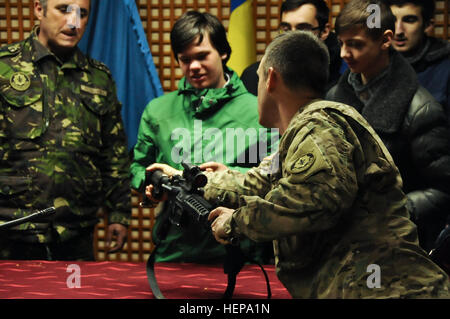 Il personale Sgt. Bruce Nemeth, un spettro elettromagnetico manager assegnato al 2° Stormo, 2° reggimento di cavalleria, mostra locale gli studenti rumeni come gestire correttamente un m4 carbine fucile durante lo studente la gita all'Smardan Area Formazione, Romania, Aprile 7, 2015. Troopers trattati i bambini per una visualizzazione dei diversi tipi di armi che un soldato americano utilizza, come pure, lasciando i bambini gusto alcuni pasti pronti al consumo (Mres). Gli studenti anche avuto modo di provare su alcuni armor tenendo un occhiata all esterno e all interno di un Stryker veicolo da combattimento. (U.S. Esercito foto di Sgt. William A. Tanner/ Foto Stock