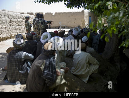 Gli abitanti di un villaggio afghano di ascoltare come un commando afghani comandante di plotone con l esercito nazionale afgano il 3° Commando Kandak parla, denunciando i talebani e i suoi seguaci, dopo una operazione di cancellazione in Panjwa'i district, 25 aprile, nella provincia di Kandahar. Il commando, uniti dal servizio degli Stati Uniti i membri, con operazioni speciali Task Force - Sud, e i membri della nazionale afghano di ordine civile di polizia, trovati talebani materiale di propaganda presso il sito e rimosso tre sospetti insorti dall'area durante l'operazione. I sospetti detenuti a Kandahar operazione di compensazione 395210 Foto Stock