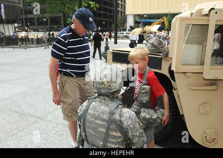 Sgt. 1. Classe Anthony L. Taylor, ottantacinquesimo supportano il comando, assiste un ragazzo provare su un esercito del cuscinetto di carico vest durante gli Stati Uniti Esercito 240th della festa di compleanno nel centro di Chicago, 10 giugno. Le quattro ore di inclusa cerimonia di soldati provenienti da tutta la terra di Chicago zona riserva Junior Officers' Training Corps cadetti, e l'Illinois esercito nazionale Guard Brig. Gen. Michael Zerbonia come senior rappresentante dell'esercito. (U.S. Esercito foto di Sgt. Aaron Berogan/RILASCIATO) esercito soldato di riserva le marce fino bambino per l'esercito, il 240th compleanno 150610-A-GI418-041 Foto Stock