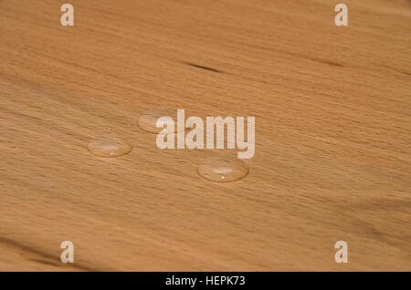 Perle di acqua su legno di faggio finito. Foto Stock