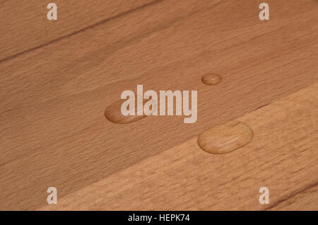 Perle di acqua su legno di faggio finito. Foto Stock