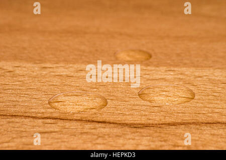 Perle di acqua su legno di faggio finito. Foto Stock