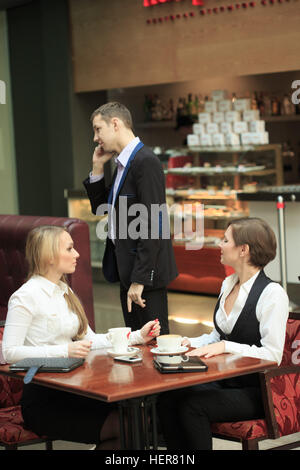 Due imprenditrice in un cafe. Un uomo guarda le ragazze Foto Stock