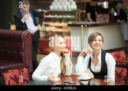 Due imprenditrice in un cafe. Un uomo guarda le ragazze Foto Stock