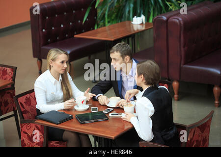 Uomini d'affari in seduta cafe per un laptop. Due ragazze Foto Stock