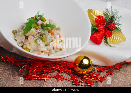 Tradizionale russa olivier insalata con il segnale di PEA su un tavolo di legno vicino a nuove decorazioni anni Foto Stock